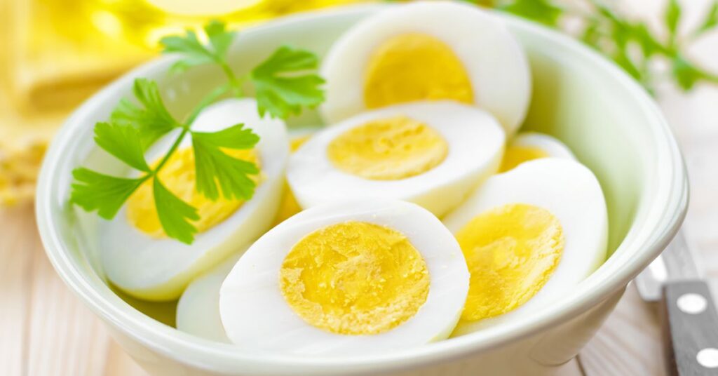 Hard boiled eggs cut in half in a white bowl with fresh parsley is just one of the 100 ways to cook an egg.