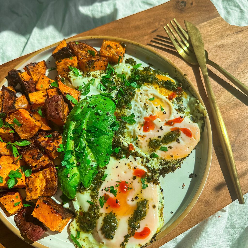 Sunny-side-up eggs with pesto and sriracha, avocado, and roasted sweet potatoes