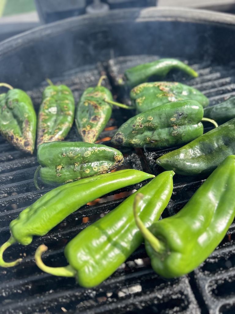Anaheim and poblano peppers partially roasted on a Kamado Joe grill.