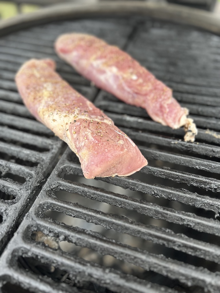 Two seasoned pork tenderloins on the grill.