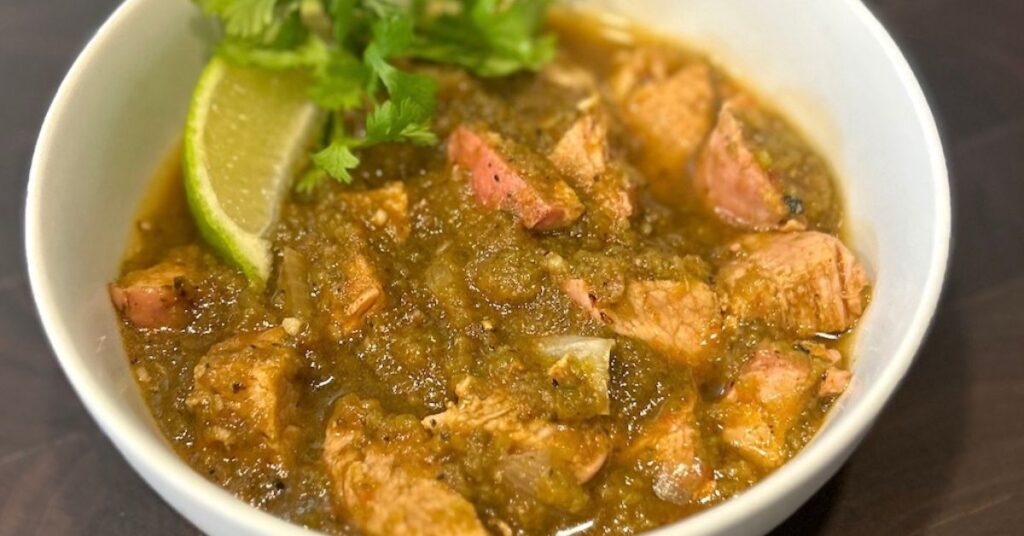Yum! Smoked green chili stew with pork and a zesty lime wedge. Topped with fresh cilantro for extra flavor.