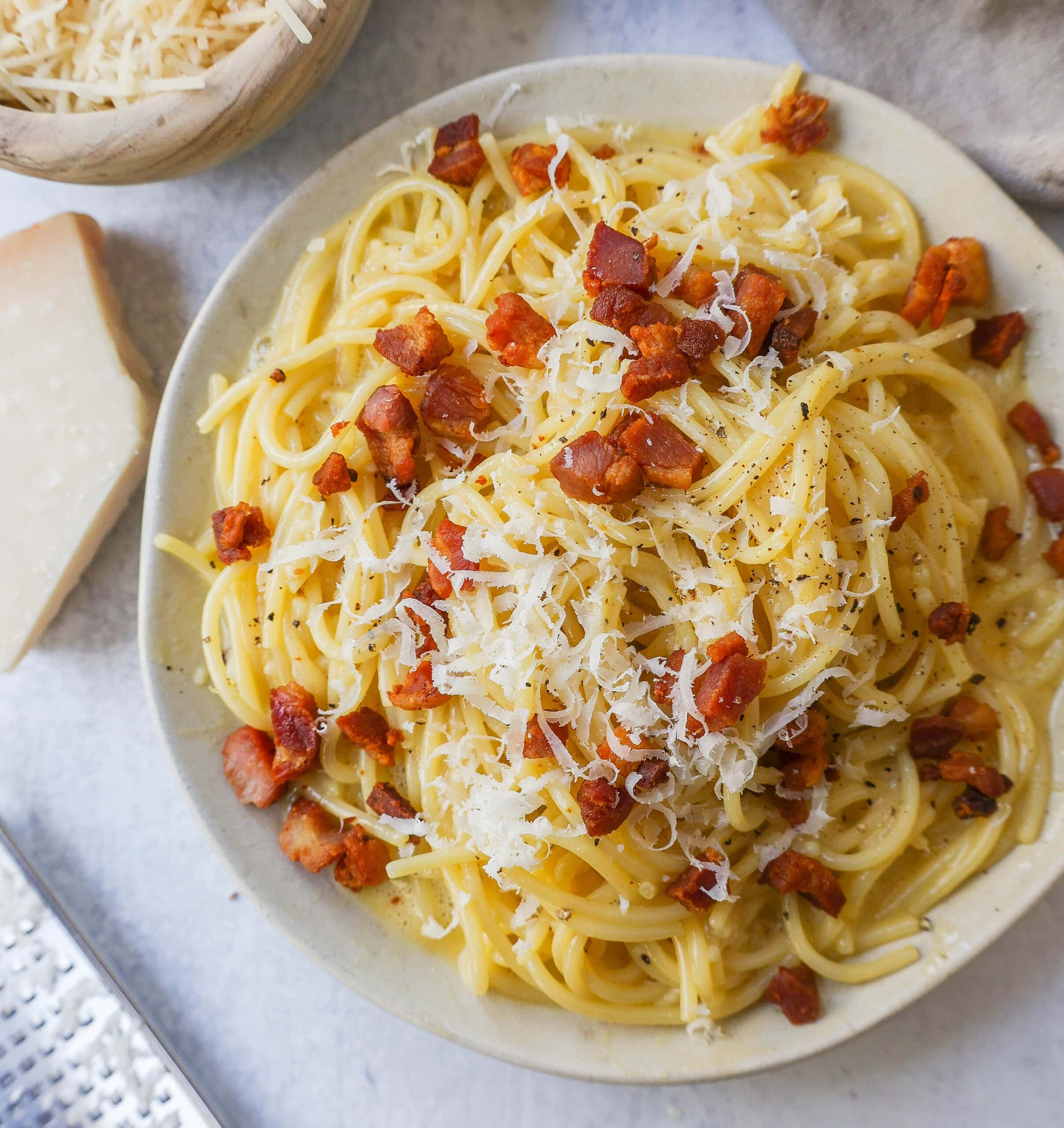 One of the 100 ways to cook an egg is this delicious spaghetti carbonara on a white plate.
