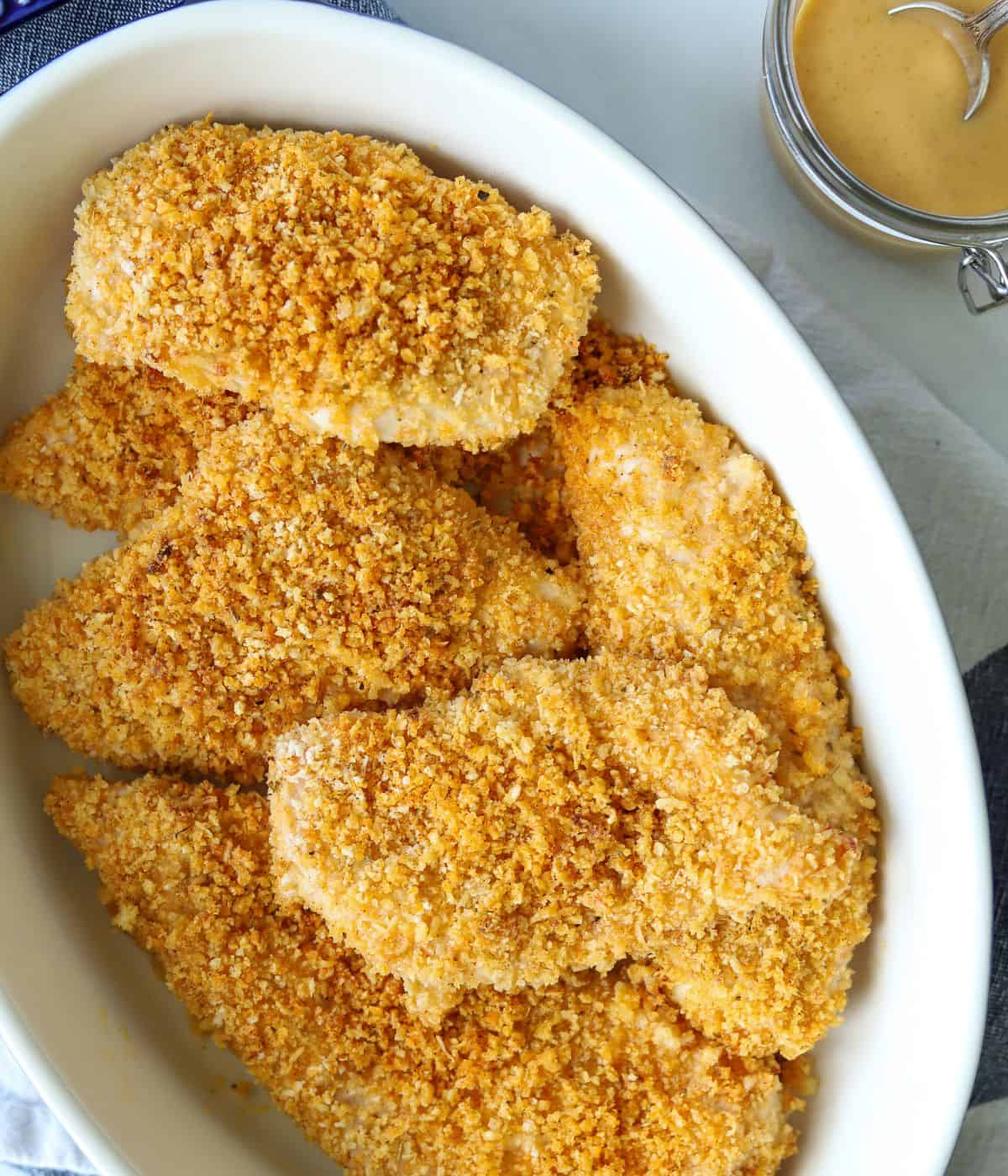 A Corning Wear dish full of baked panko crusted thinly sliced chicken breasts.