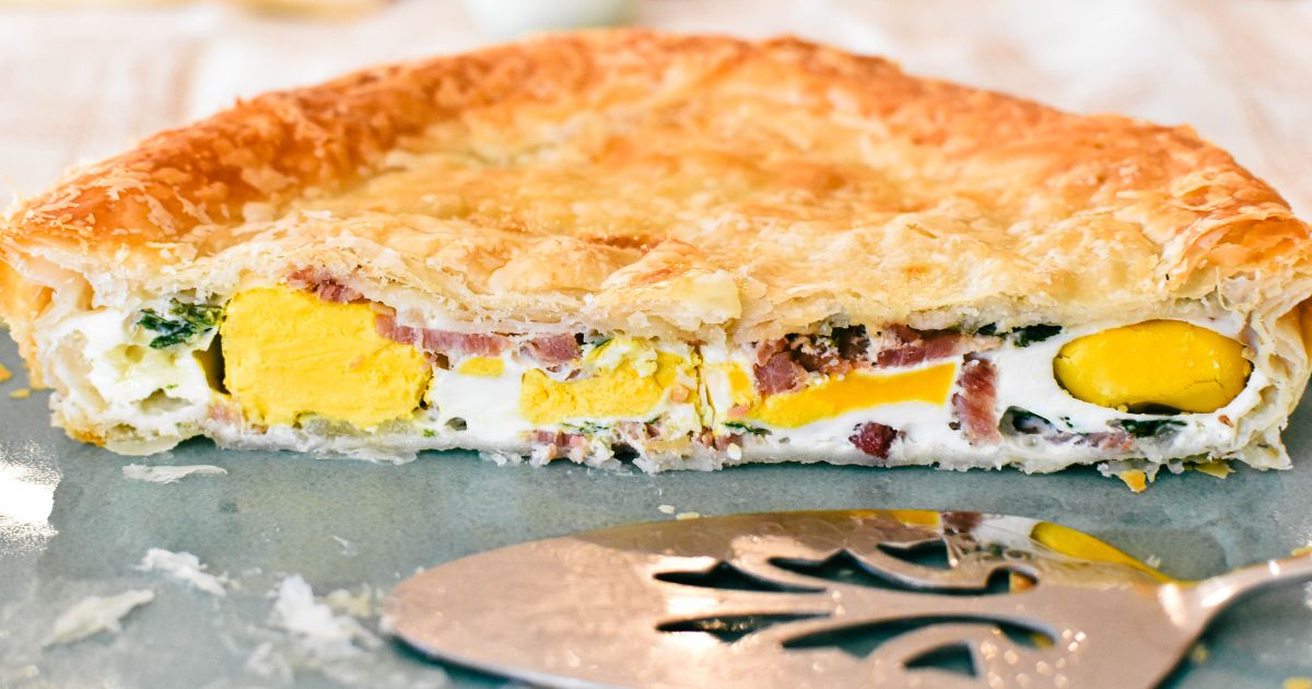 An egg and bacon pie on a cutting board.