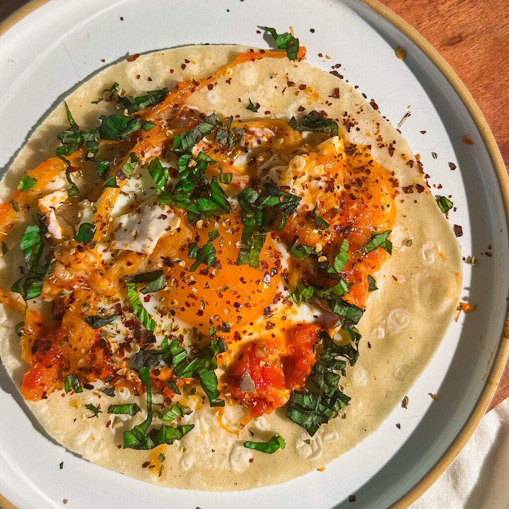 Spicy breakfast tortilla with fried egg, cheese, and fresh herbs