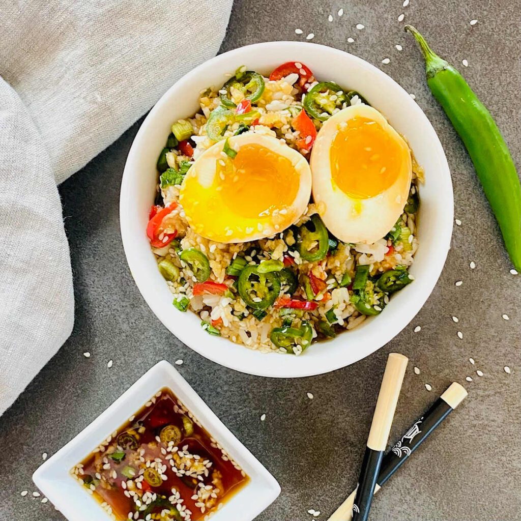 Spicy jalapeno rice bowl with soft-boiled eggs, sesame seeds, and soy chili sauce