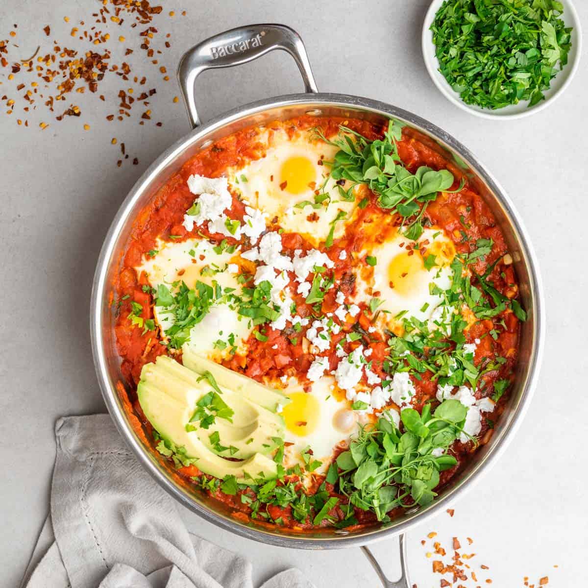 A spicy shakshuka in a skillet on a white counter top.
