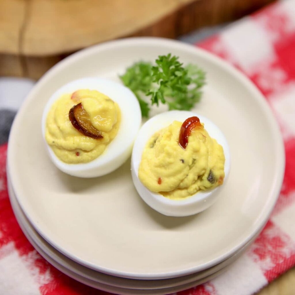 10+ Recipes Using Cowboy Candy Jalapeno deviled eggs garnished with parsley on a white plate.