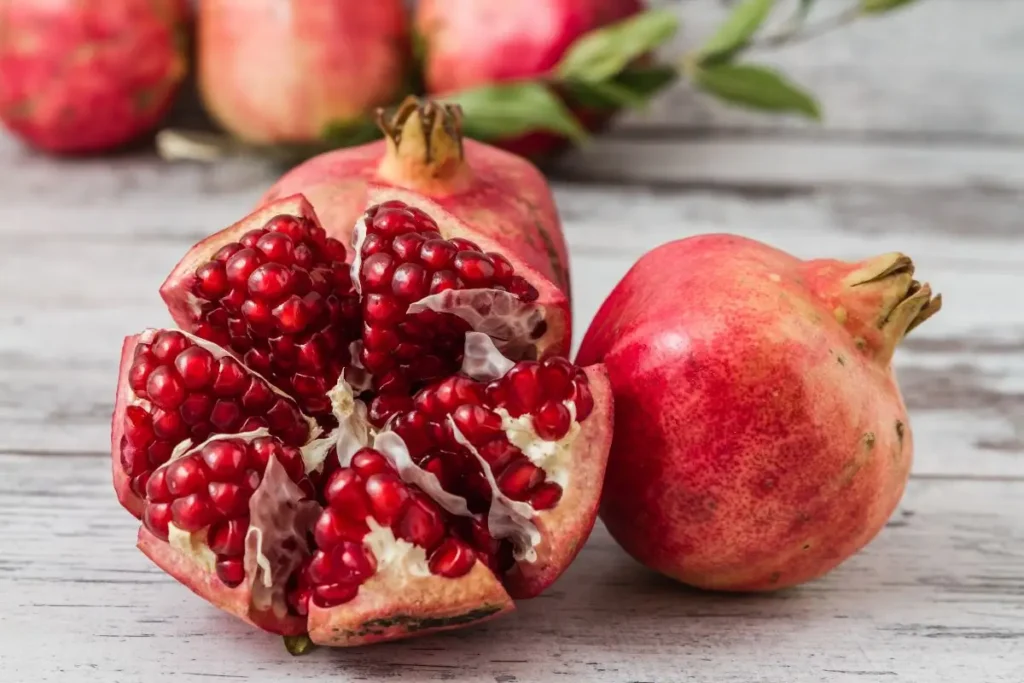 An open pomegranate revealing its jewel-like ruby red seeds, or arils, surrounded by the bright red skin. Pomegranates are a quintessential November seasonal produce, offering a burst of flavor and nutrients like antioxidants.