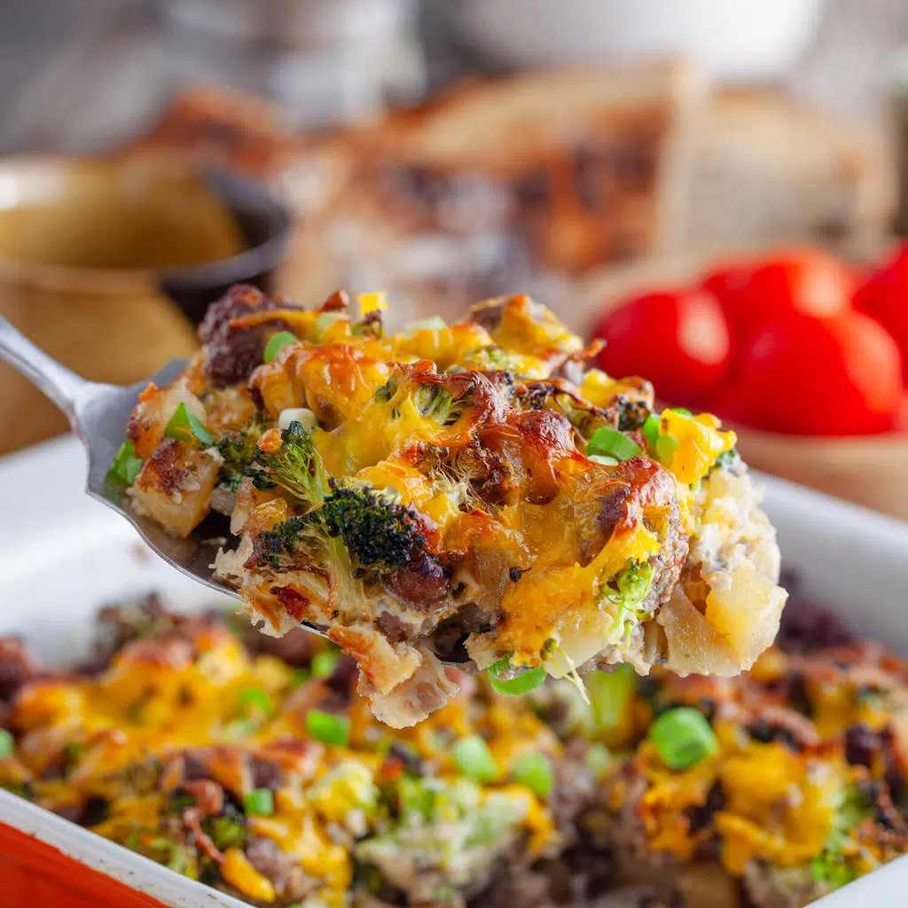 Potato Sausage Broccoli Breakfast Casserole A forkful of Potato Sausage Broccoli Breakfast Casserole being scooped warm from the casserole dish.