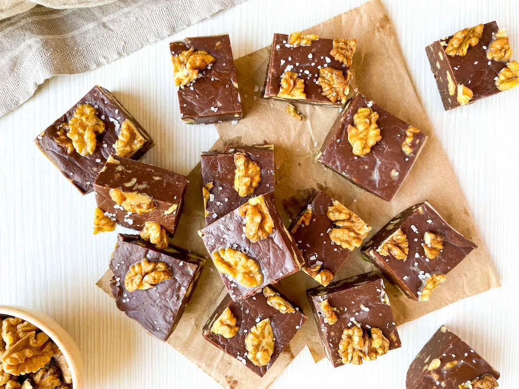 Chocolate Walnut fudge on a piece of parchment paper on a white background.