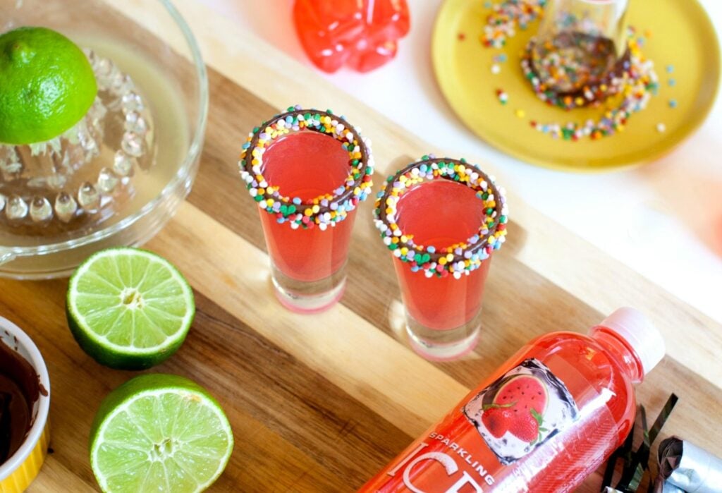 6 New Year's Eve Shots Pink strawberry lime shots with sprinkle rims on wooden board