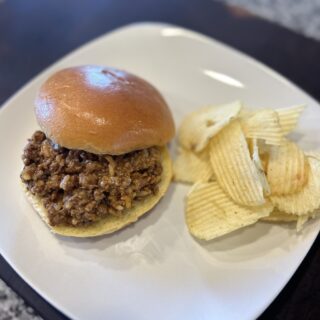 Sloppy Joe with Chicken Gumbo Soup on a white plate with potato chips.