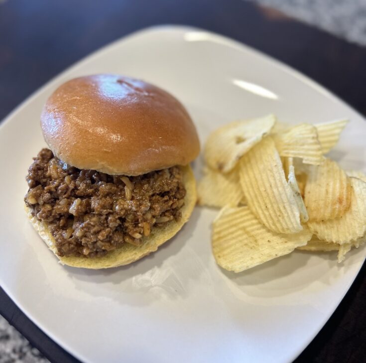 Sloppy Joe with Chicken Gumbo Soup on a white plate with potato chips.