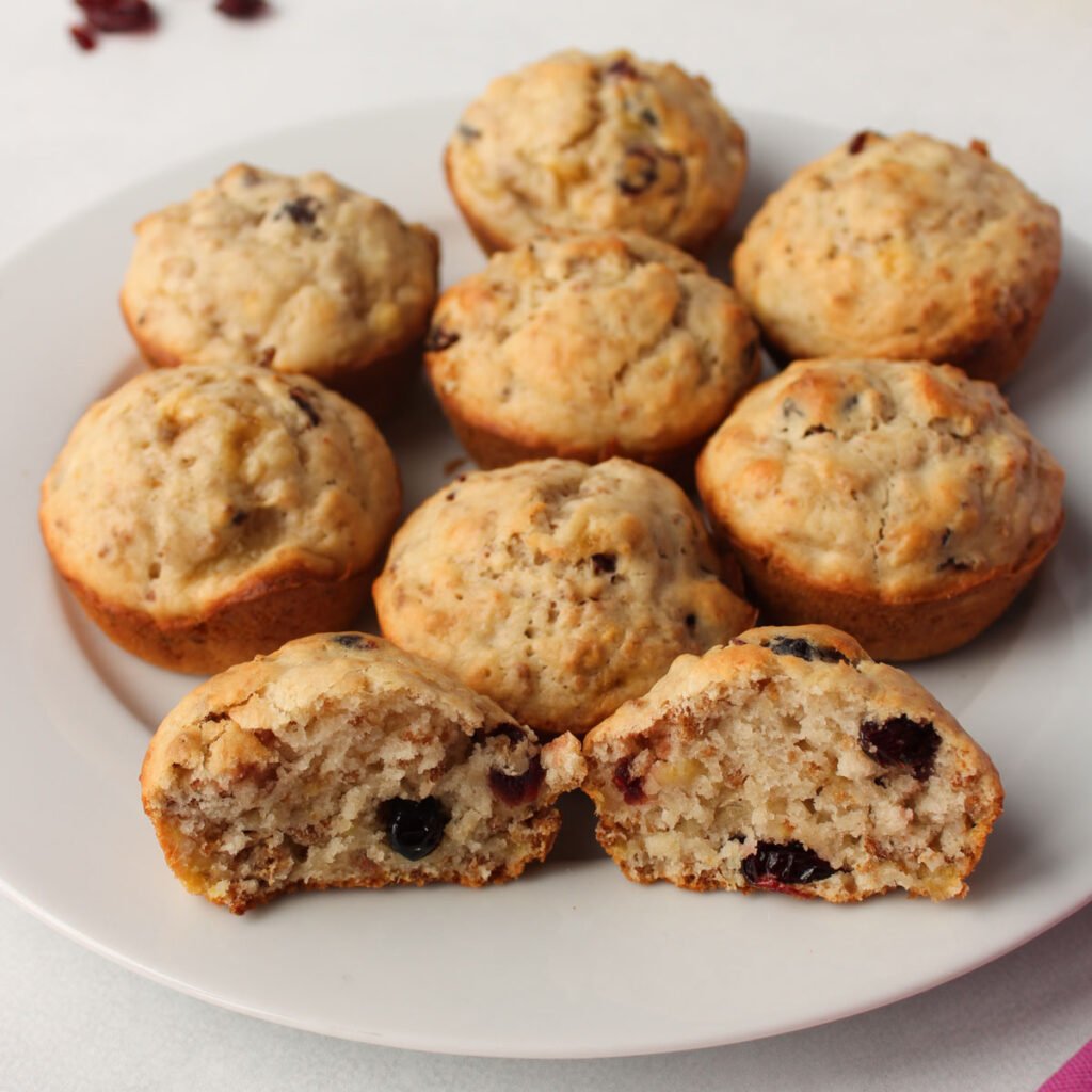 Homemade berry muffins on a white plate, one sliced open