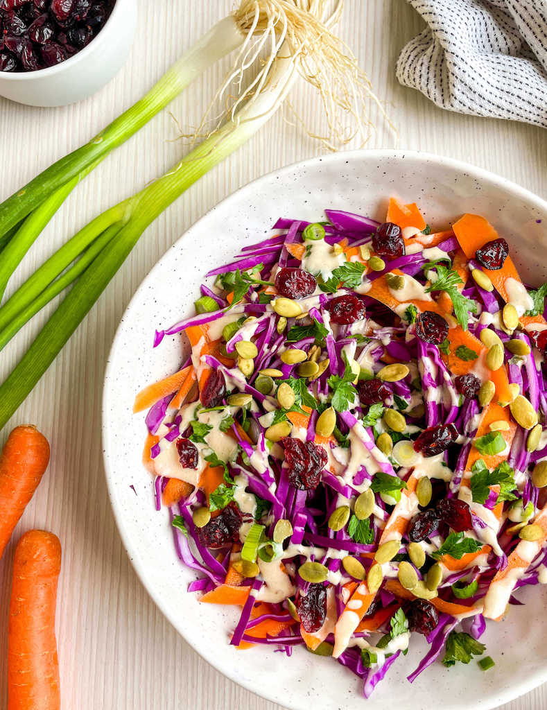 Red cabbage and carrot salad with lemon tahini dressing in a stoneware bowl.