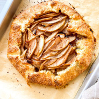 A rustic pear galette on a parchment paper lined baking sheet.