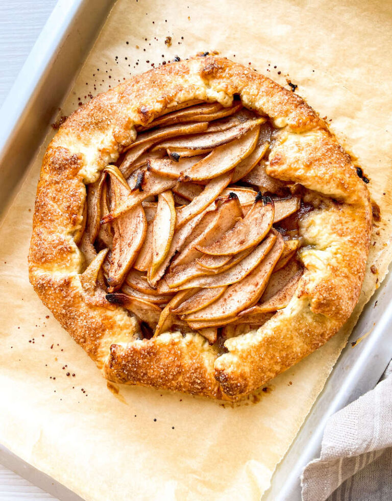 A rustic pear galette on a parchment paper lined baking sheet.