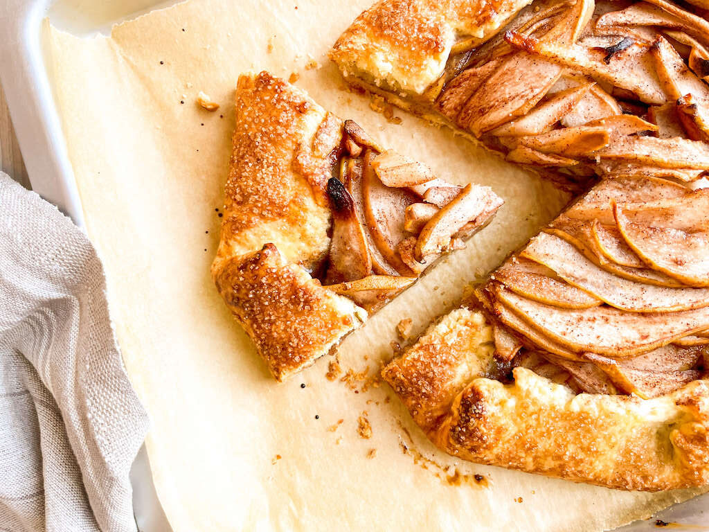 A rustic pear galette sliced for serving on parchment paper.