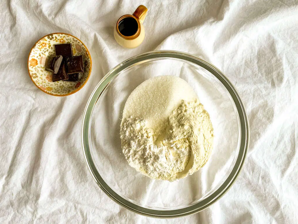 A glass mixing bowl filled with flour, sugar, salt, and cornstarch to make the chocolate kahlua tart crust.