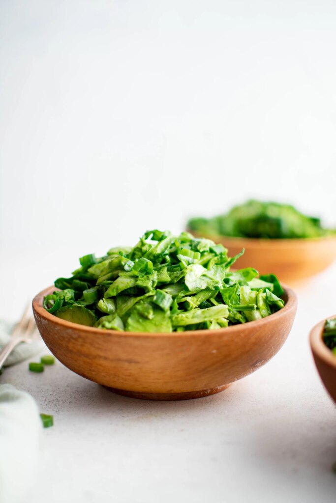Chopped green salad with lettuce and scallions in a wooden bowl