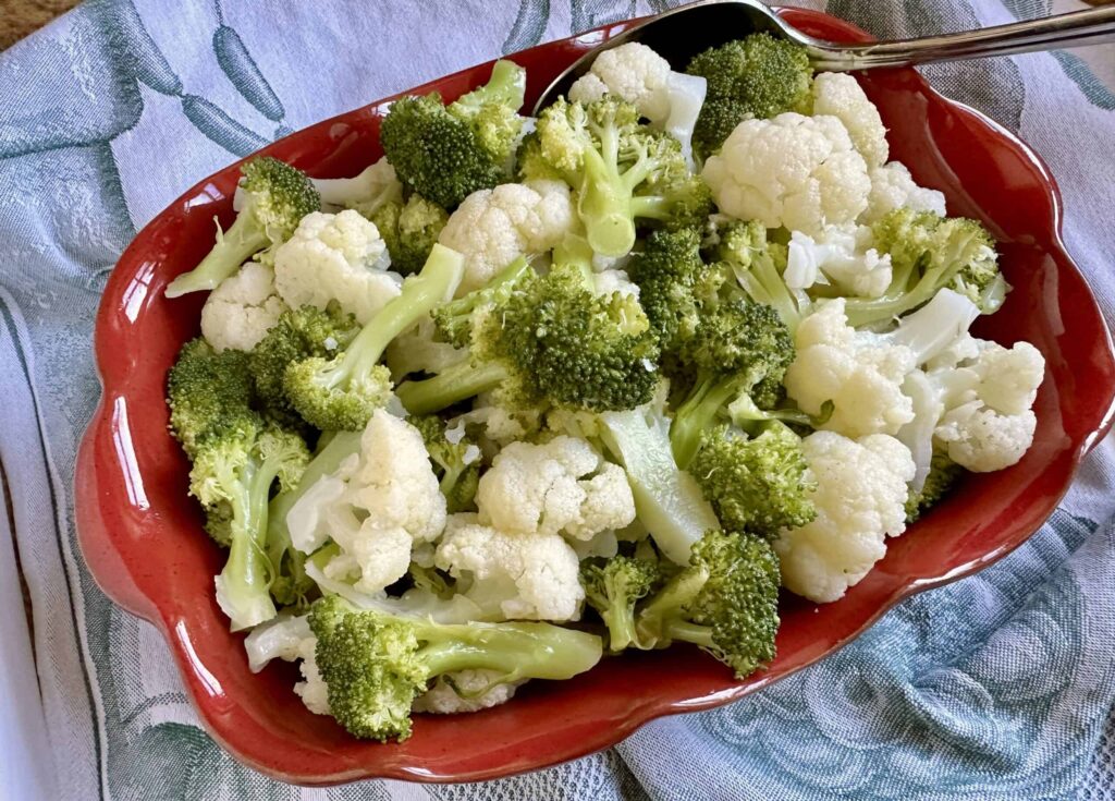 Steamed broccoli and cauliflower florets in a red serving dish
