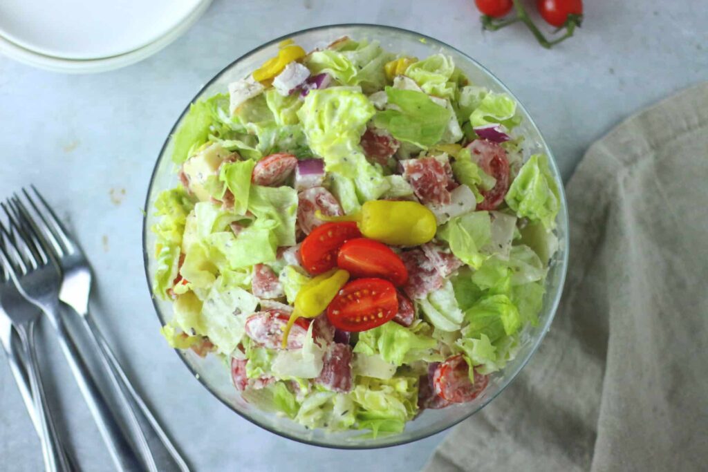 Italian chopped salad with lettuce, tomatoes, peppers, salami, and creamy dressing