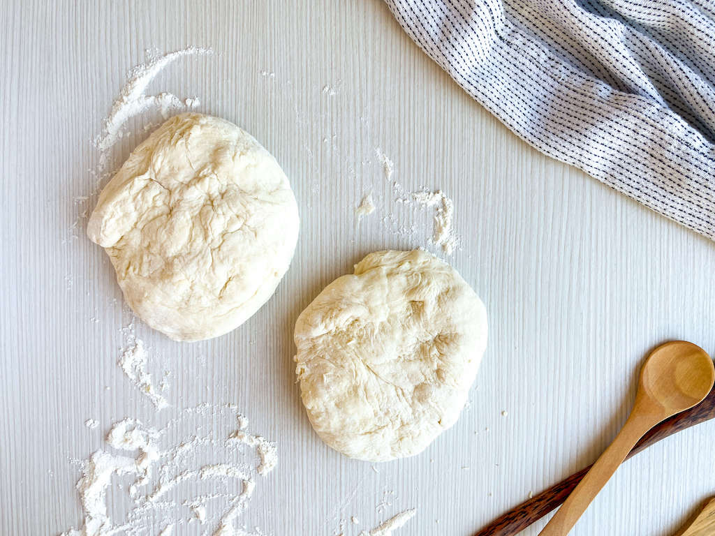 Two balls of no knead pizza dough on a counter top.