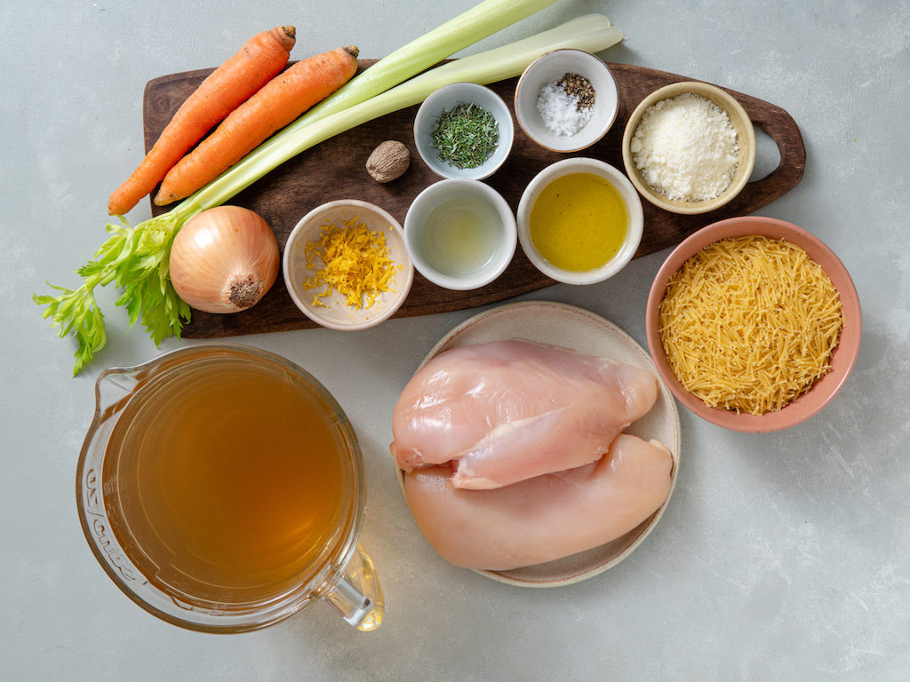 Ingredients for chicken fideo soup including carrots, celery, onions, spices and chicken breasts.