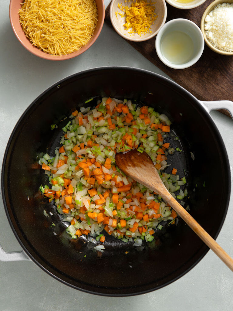 Carrots, celery, and onion being sauted in a dutch oven pot.