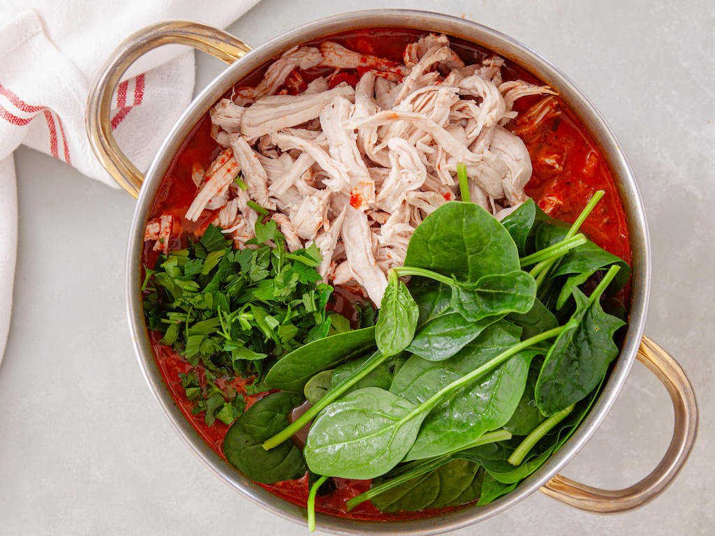 Adding the turkey, baby spinach, and fresh parsley to the leftover turkey and barley soup recipe.