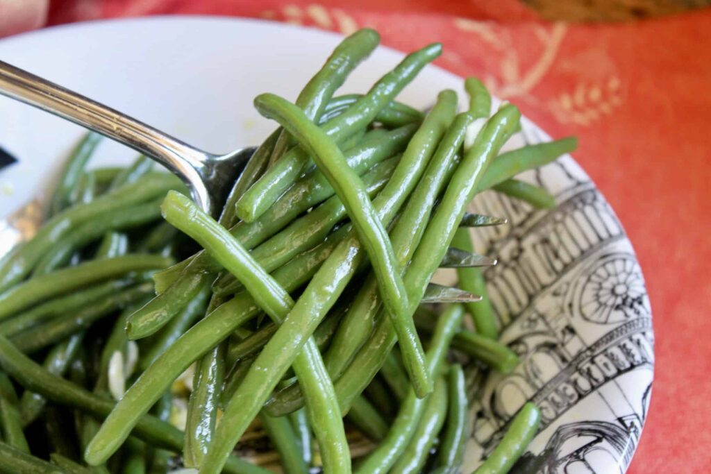 Close-up of glossy sautéed green beans on a fork
