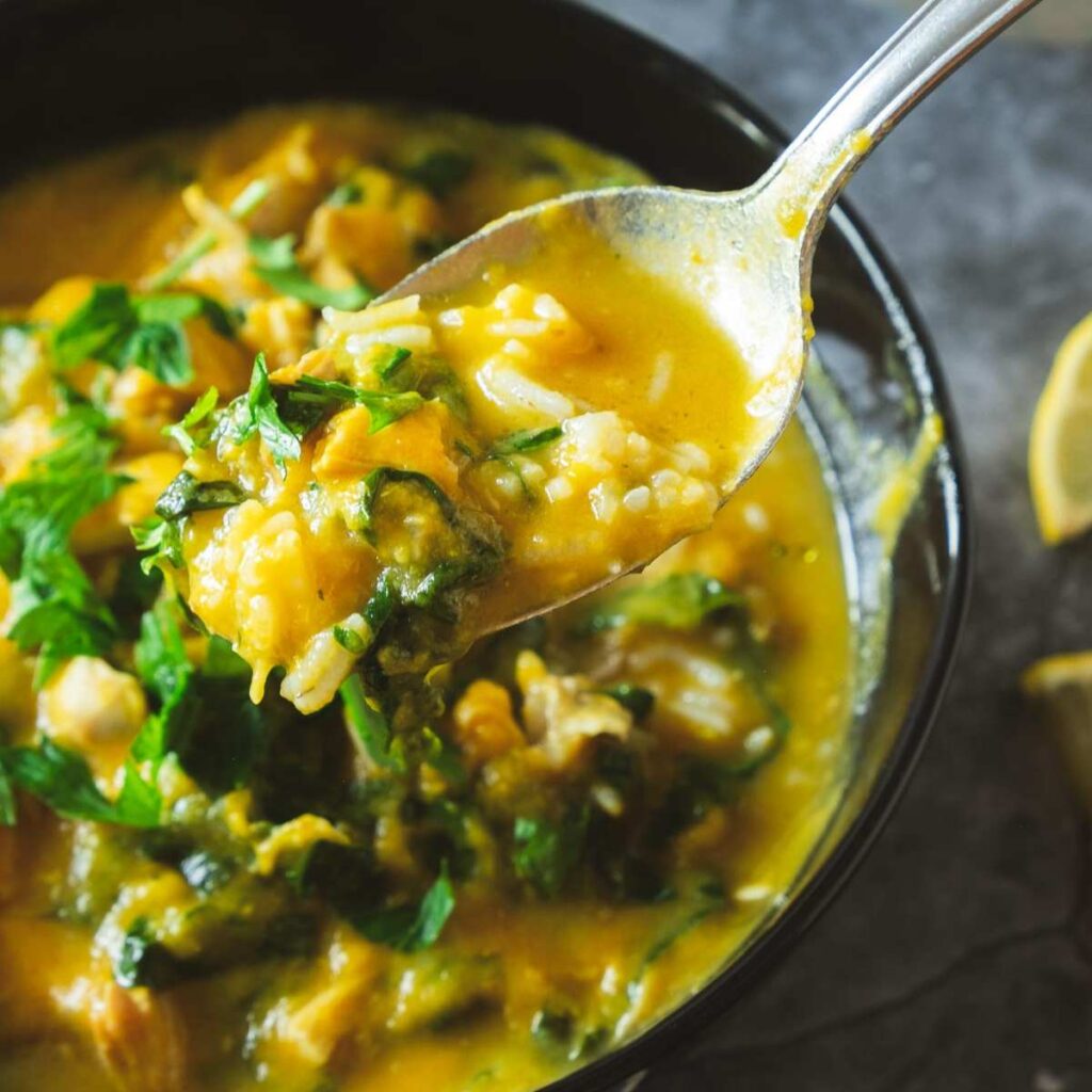 Close-up spoonful of creamy vegetable rice soup with fresh herbs in a bowl
