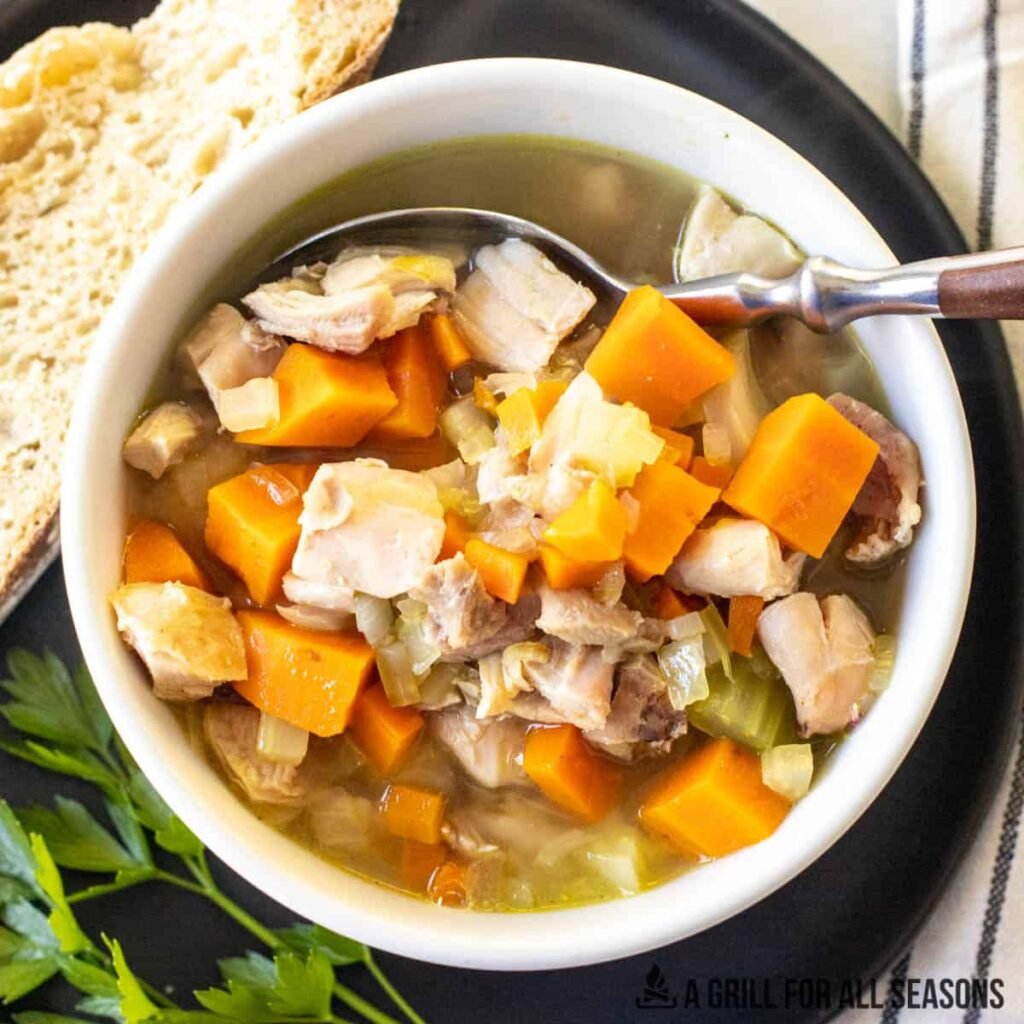 Hearty homemade chicken vegetable soup with carrots and celery, spoon and bread