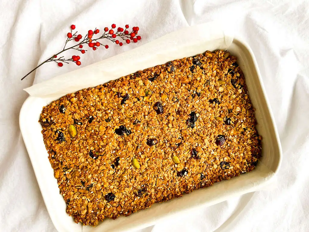 A pan of pistachio granola bars baked until golden brown cooling on a baking rack.