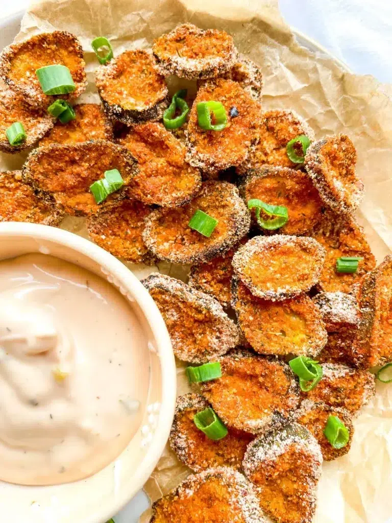 A plate of baked crispy pickle chips with sauce.