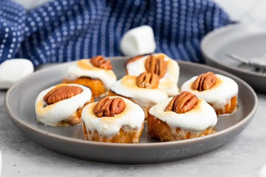 Plate of sweet potato bites appetizer with marshmallows and pecans, showcasing golden-brown marshmallow topping. Ideal as a festive and easy holiday snack.