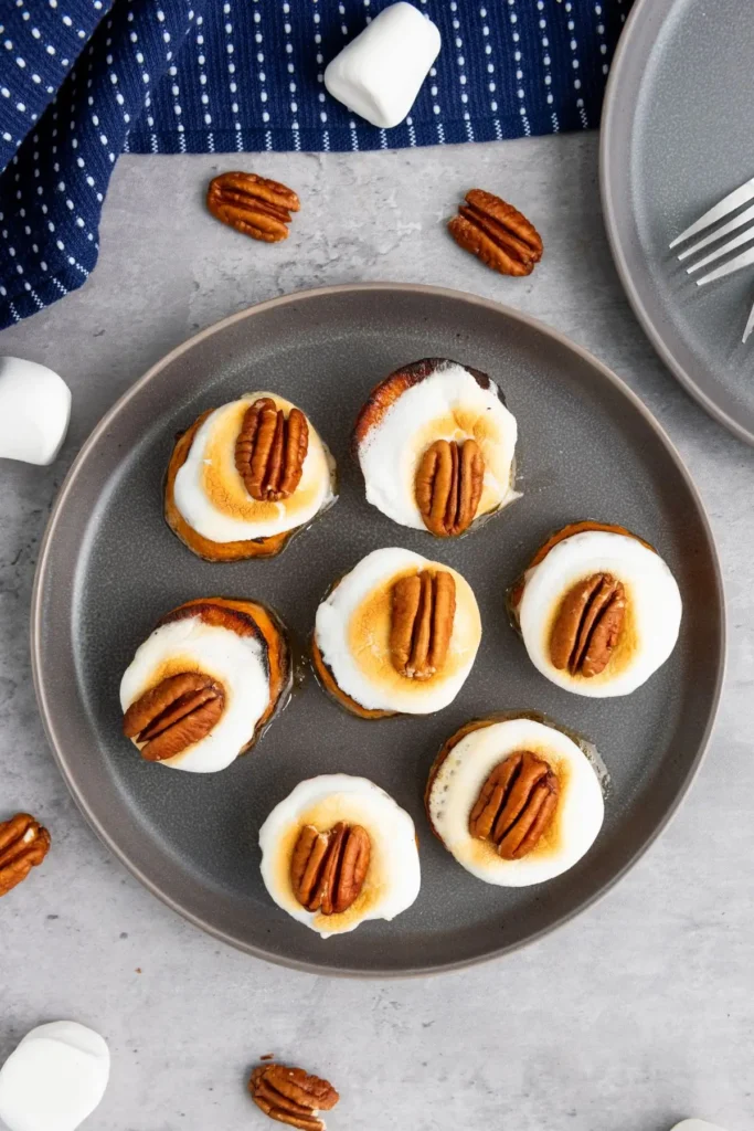 Sweet potato rounds with marshmallows and pecans on a gray plate, caramelized to perfection for a roasted sweet potato recipe idea.