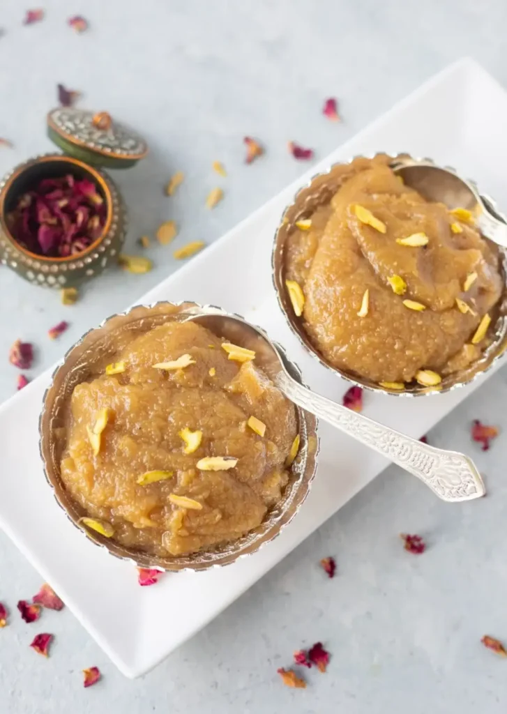 A creamy Indian dessert, Badam Halwa, garnished with slivered almonds and served in decorative bowls, showcasing its rich texture.