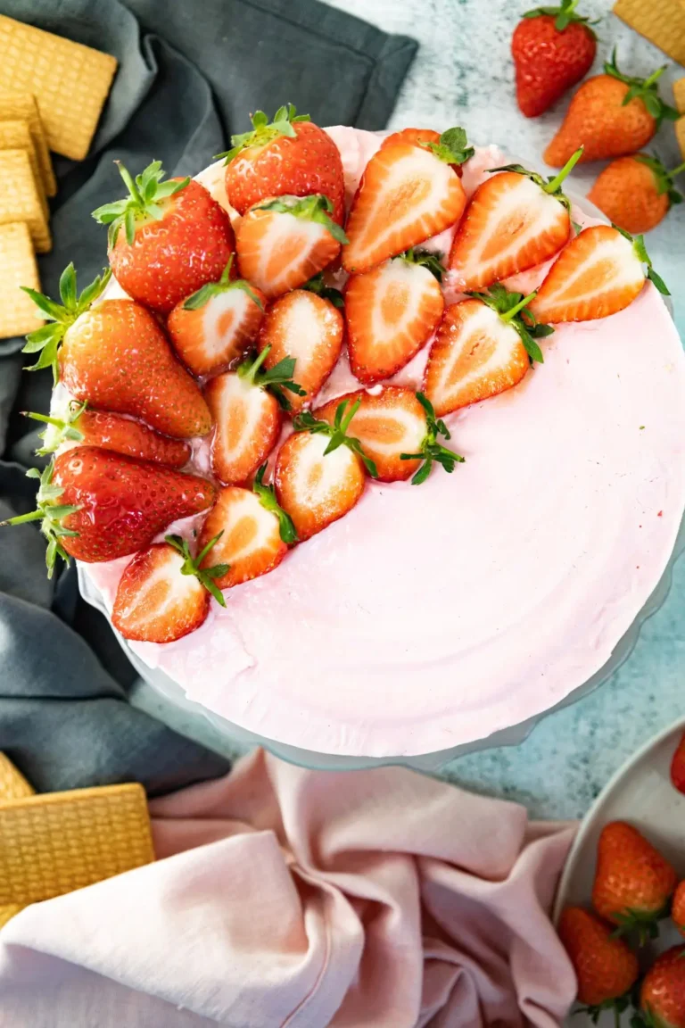 Pink frosted dessert cake topped with fresh halved strawberries