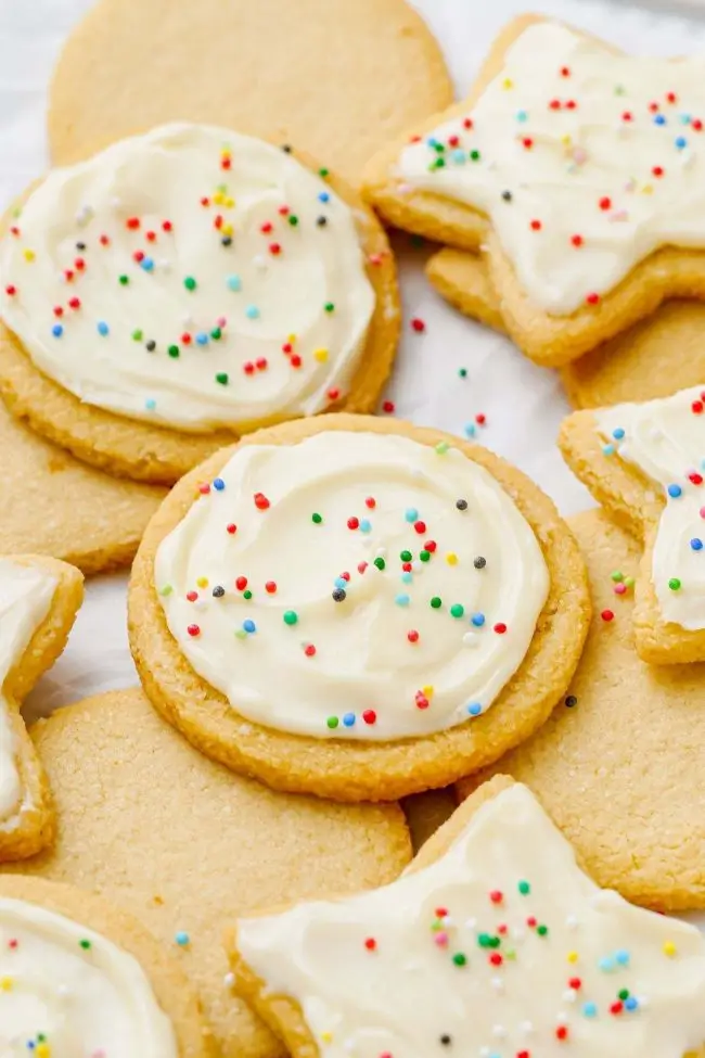 A delightful plate of almond flour sugar cookies topped with creamy frosting and colorful sprinkles. These gluten-free treats are perfect for holiday baking or a sweet snack.