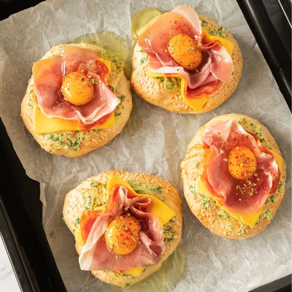 Bagel brunch idea featuring egg, prosciutto, and salami, served alongside fresh parsley and chili paprika.