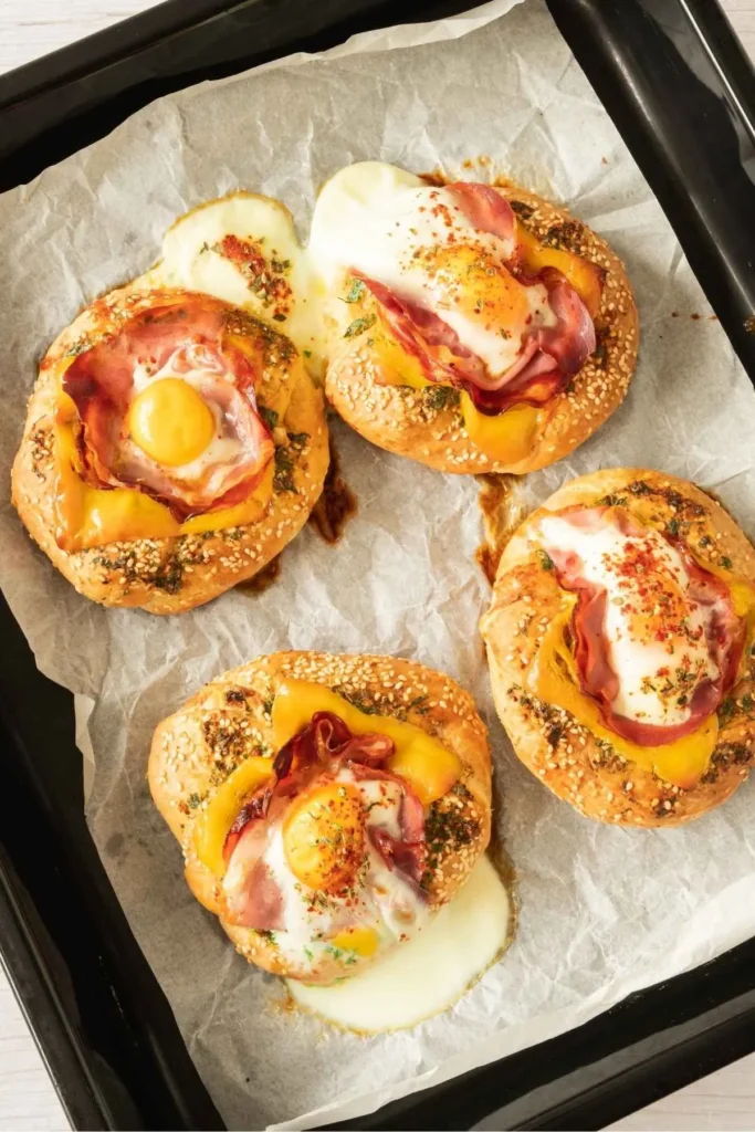 Mini breakfast food idea with toasted bagel, baked egg, prosciutto, and garlic butter for a savory twist.