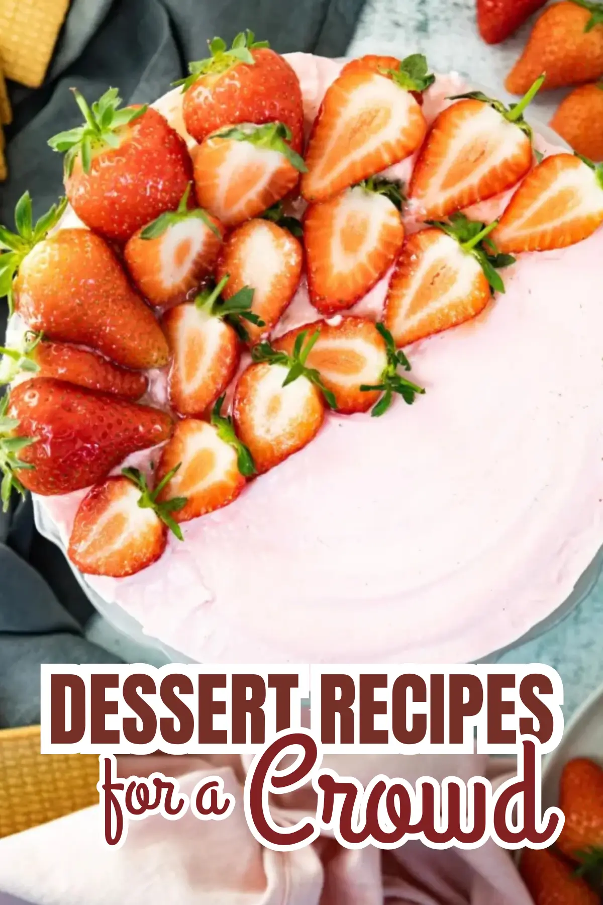 Overhead view of pink strawberry cake with fresh halved berries, great for a crowd