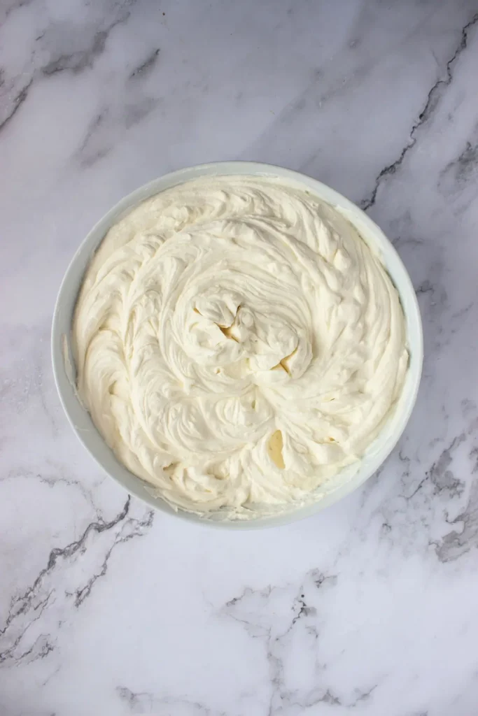 A bowl of smooth mascarpone cream, prepared for an easy tiramisu recipe, ready to be layered into a mini torte.