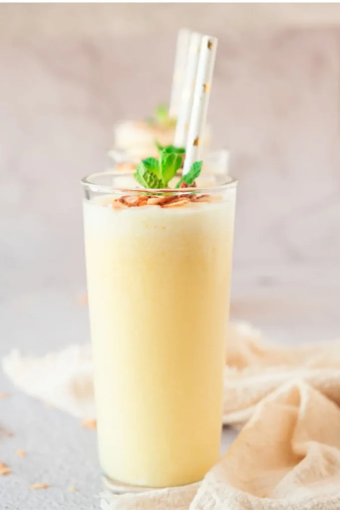 Creamy pineapple soda recipe served in a tall glass, garnished with mint leaves and coconut flakes. A refreshing nonalcoholic fruit soda drink perfect for summer.