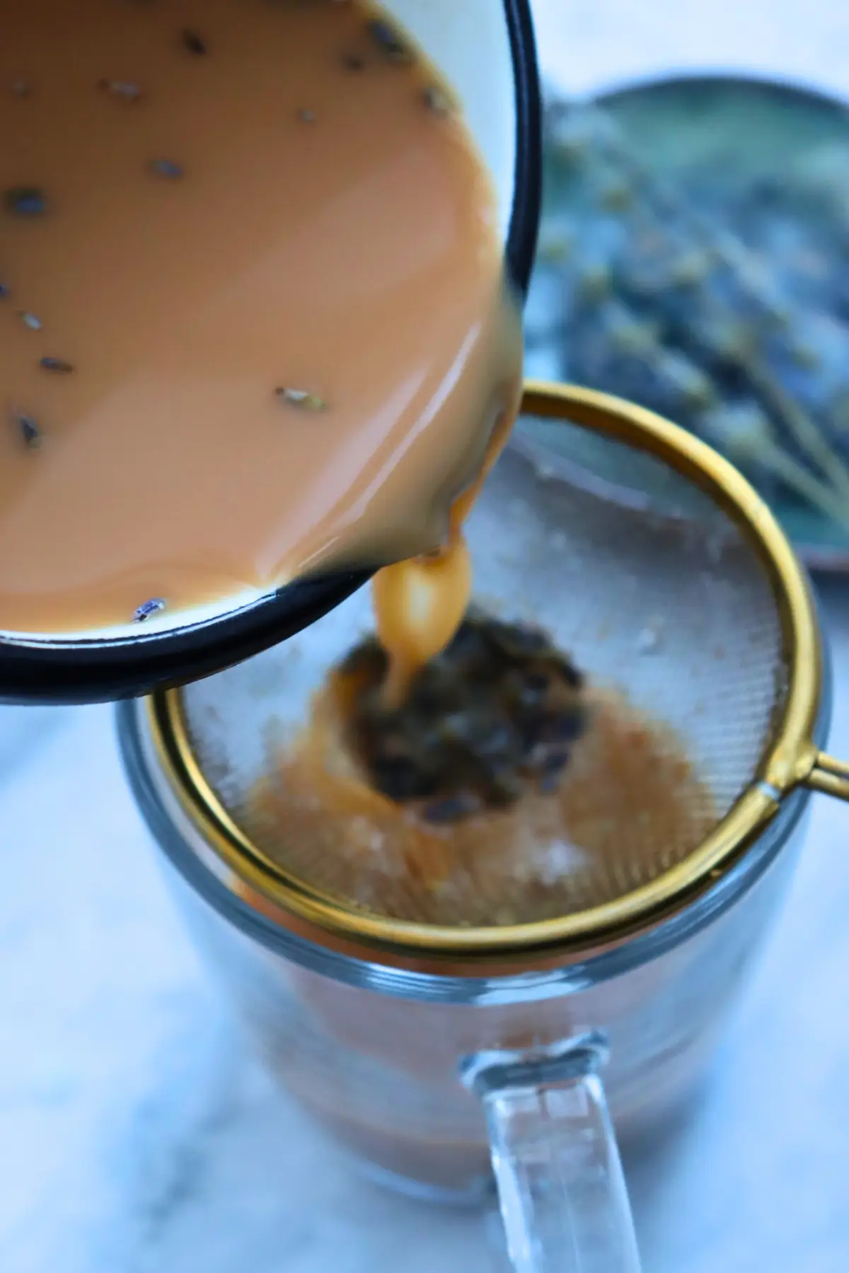 Pouring homemade London Fog latte through a strainer with almond milk