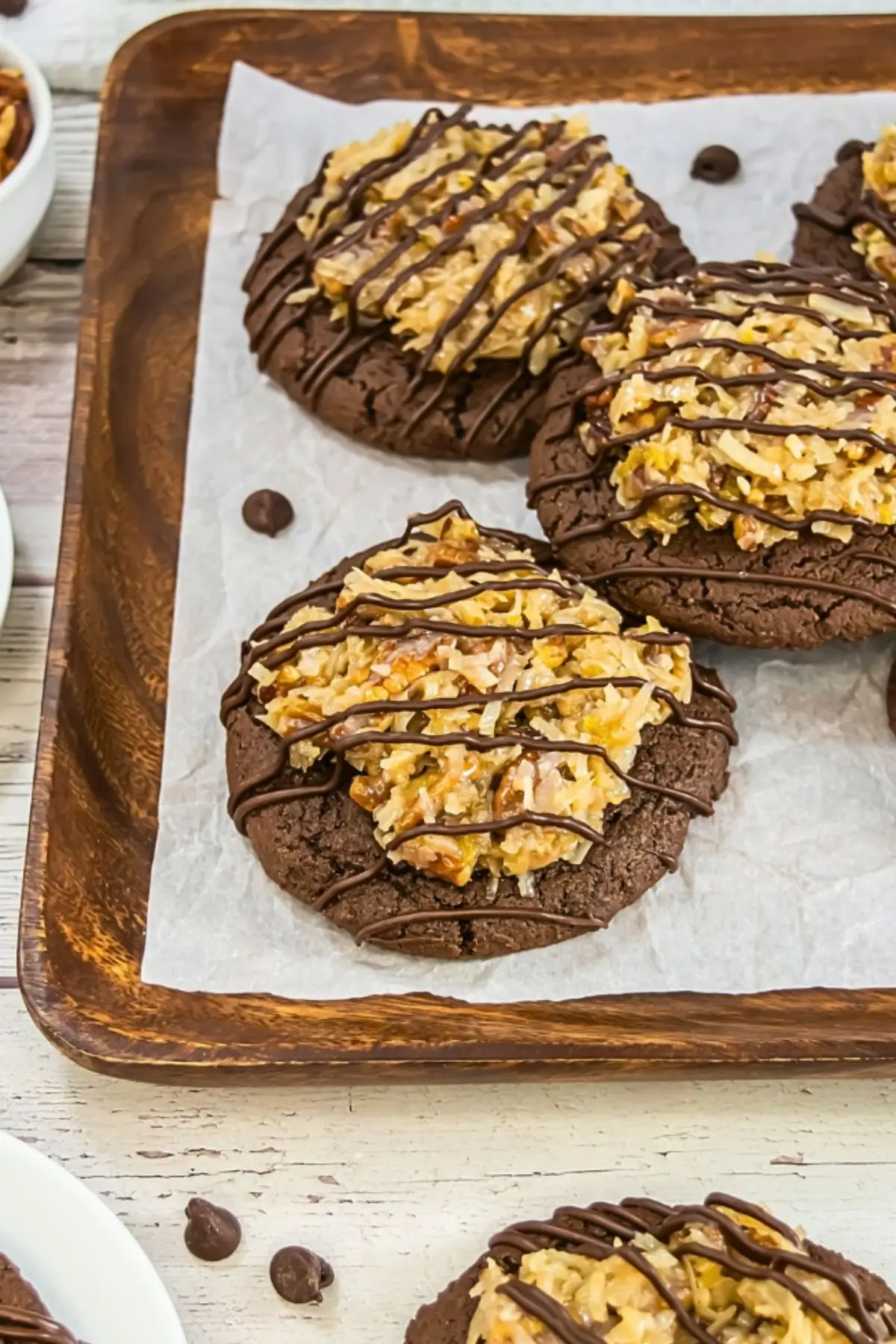 German Chocolate Cake Crumbl Cookies Batch of Crumbl-style German chocolate cookies on a tray, topped with rich coconut pecan frosting and drizzled with melted chocolate.