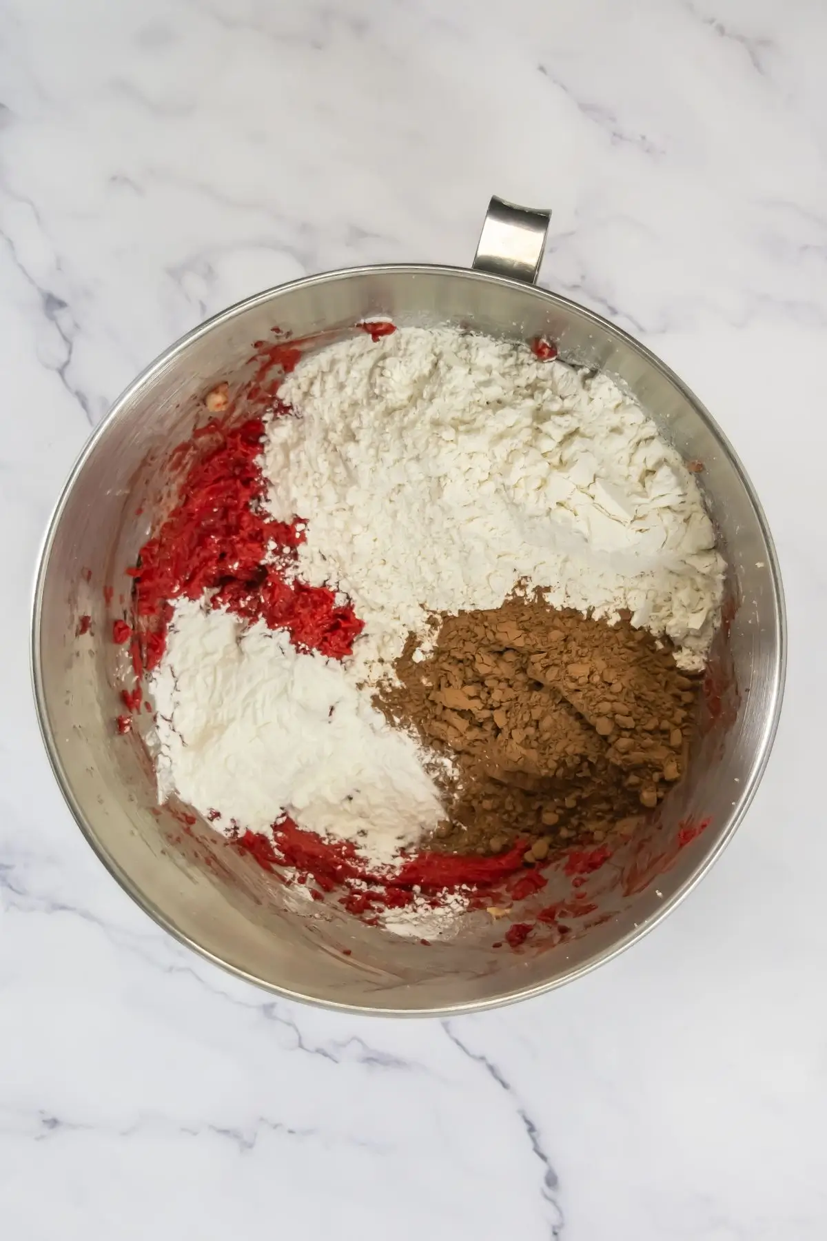 Red Velvet Crumbl Cookies (Crumbl Copycat) Mixing bowl with red wet batter for an easy dessert, adding flour, cocoa powder, and other dry stuf