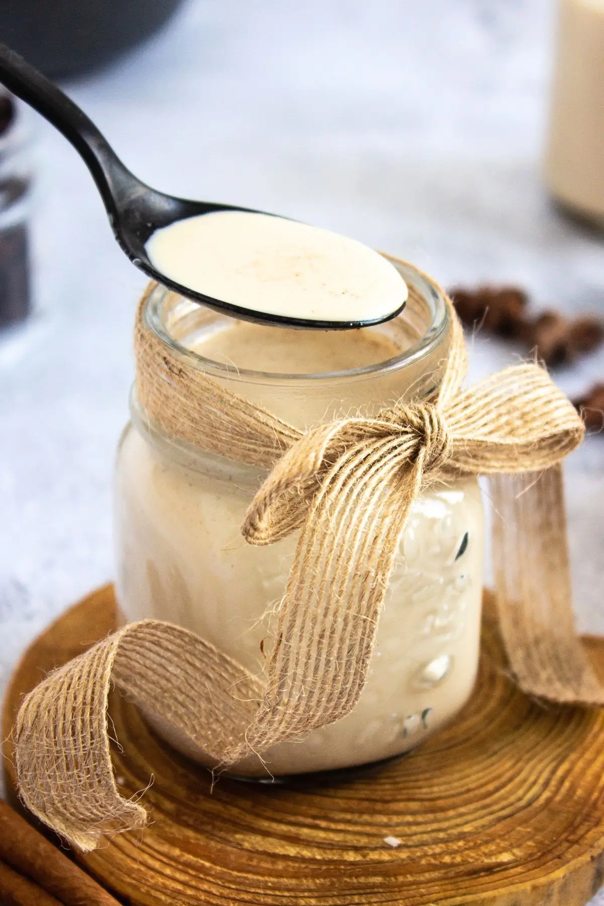 Black spoon scooping Cinnabon-inspired coffee creamer from a rustic mason jar